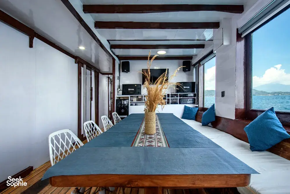 Phinisi dining table in an onboard lounge with ocean views on La Famille’s private 3D2N Komodo cruise in Labuan Bajo