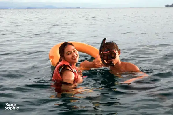Snorkelling couple smiling in masks with an orange life ring during a private sunset yacht sail from Kota Kinabalu