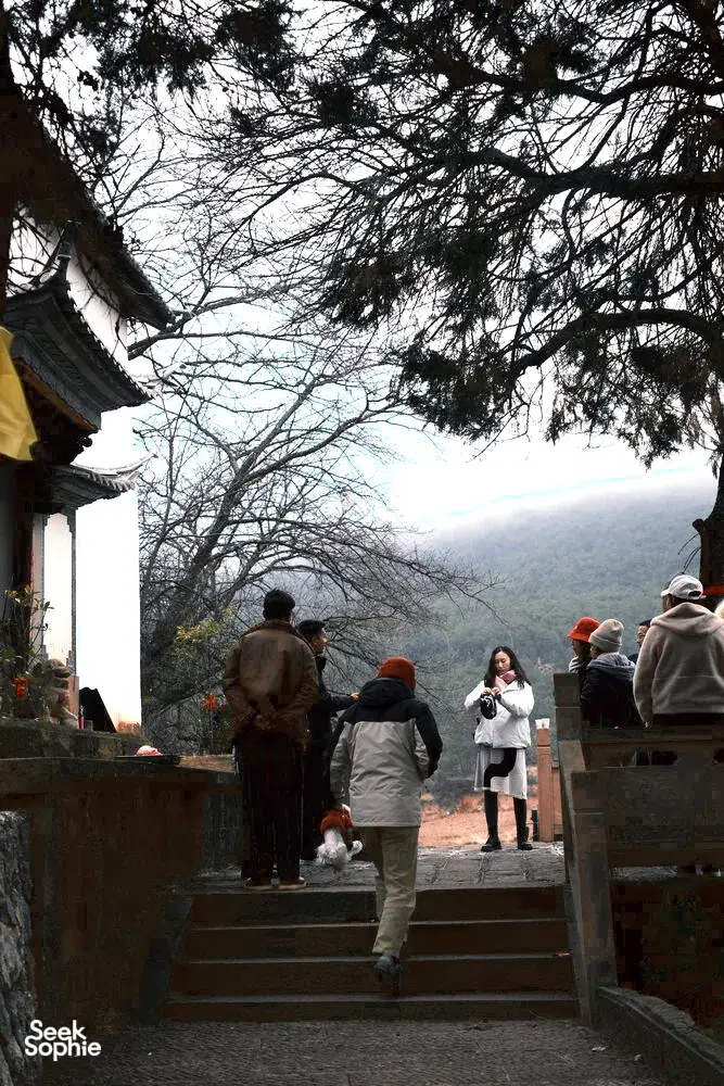 Wisatawan menaiki tangga batu di samping bangunan tradisional menuju perbukitan berkabut di Shaxi, Dali, sebagai bagian dari retret ramah lingkungan 2 hari 1 malam