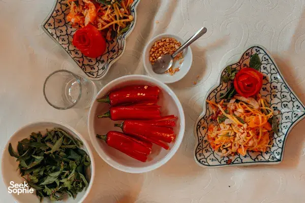 Jolie Cooking Class in Hoi An: overhead spread of fresh chillies, lettuces and sprouts on a decorated table during Vietnamese home cooking
