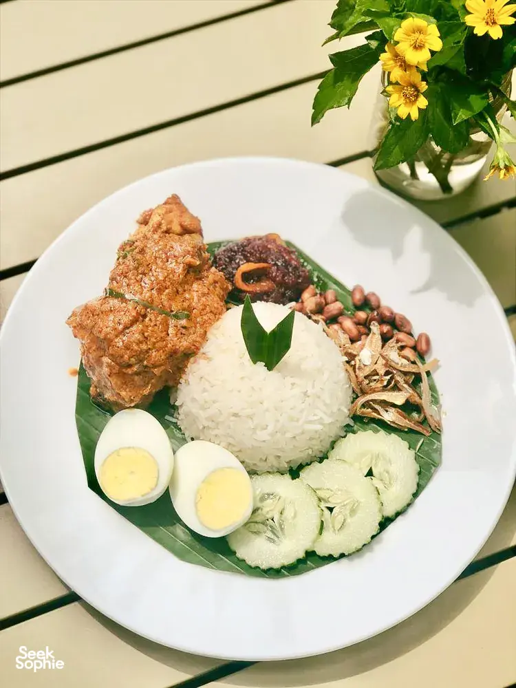Plate of Malaysian comfort food with white rice, sliced cucumber, boiled eggs and fried chicken, served on banana leaves at Langkawi