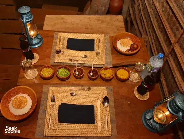 Overhead dining scene with two place settings, curries and rice on a woven table at The Elephant Next Door restaurant in Udawalawe