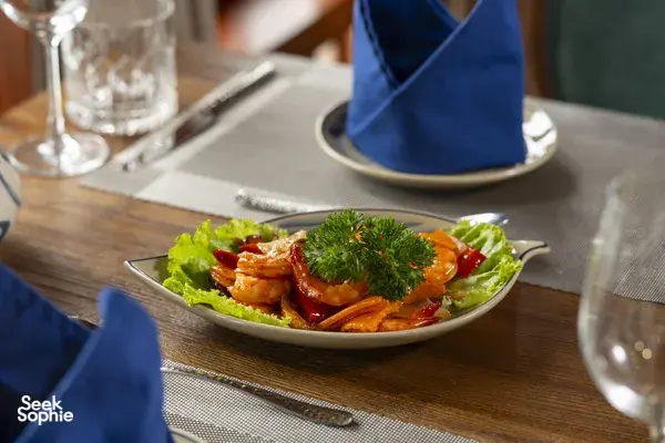 Four-course-style seafood lunch on a Cat Ba boutique cruise, with shrimp and herbs served at a wooden table
