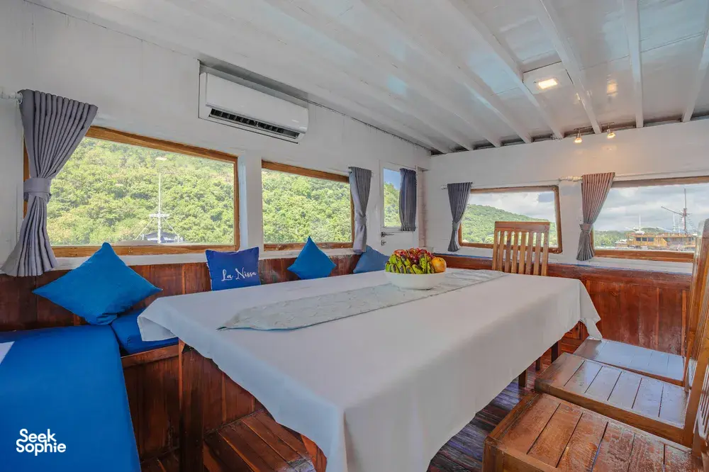 Onboard cabin with twin beds, blue cushions and large windows, for restful stays on a 3-day join-in Komodo boat trip in Labuan Bajo