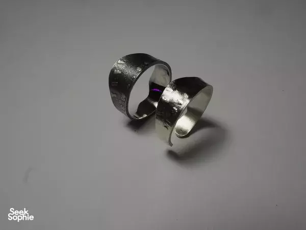 Two handmade silver rings with a brushed finish on a plain background from a Singapore silversmith workshop for workshops in Singapore