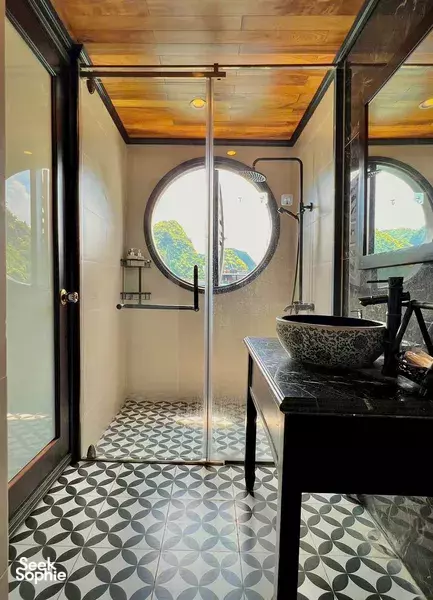 Bathroom on a Cat Ba Ocean Cruises cabin with a round porthole window, sink and patterned floor tiles on a 2D1N Cat Ba cruise