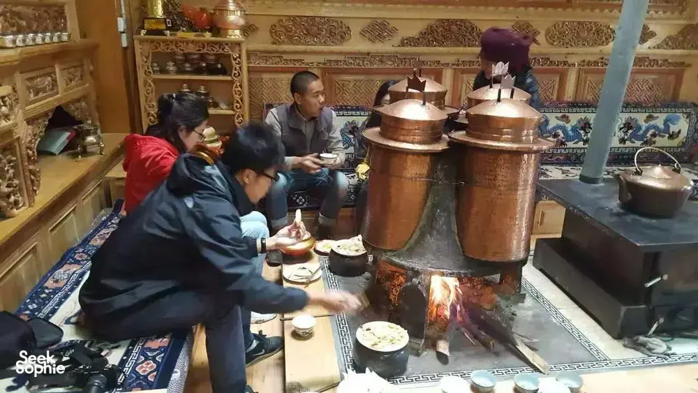 Copper cooking pots and an open flame over a stove during a Tibetan home lunch in Shangri-La, in the family kitchen