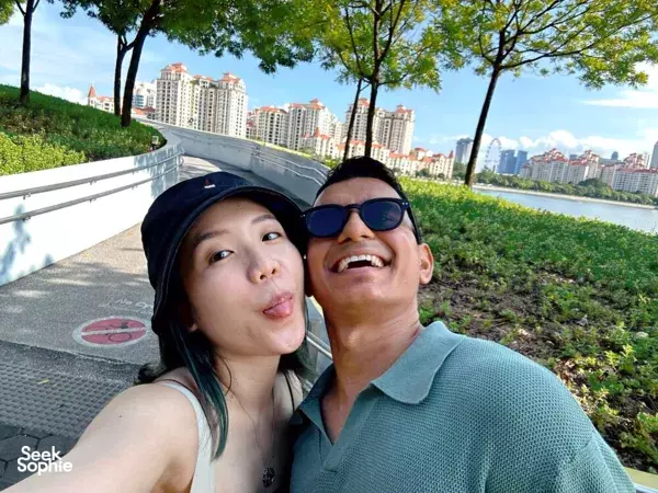Two people smiling on a riverside walkway with Singapore skyline during a HarbourFront team puzzle adventure, Singapore hidden gems