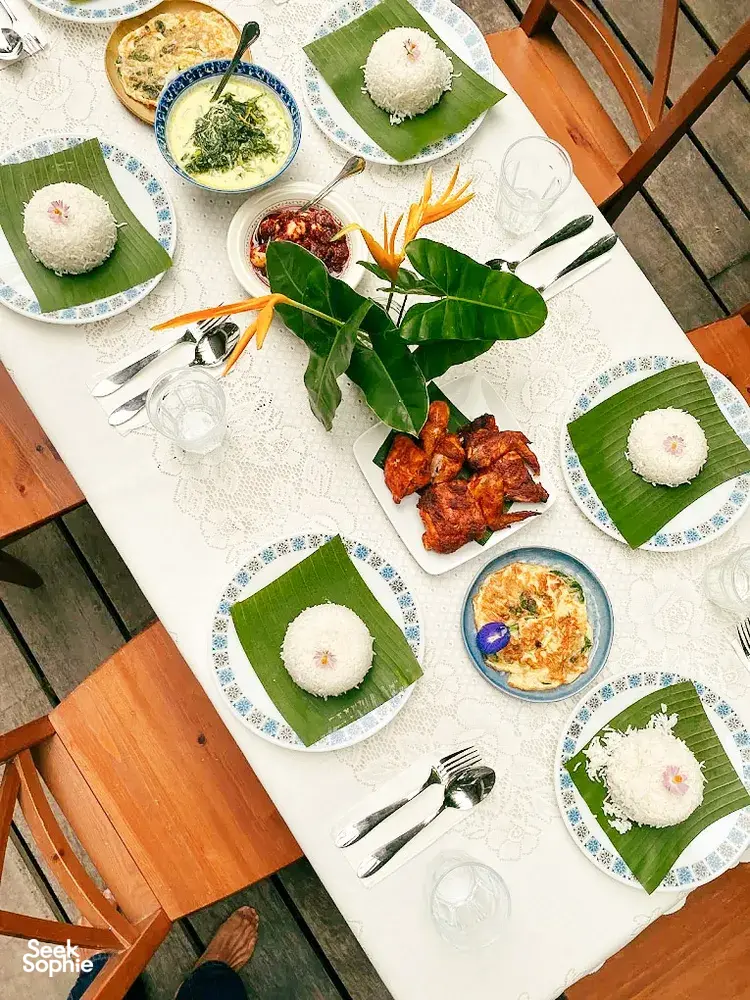 Malaysian comfort-food meal spread on plates and banana leaves at Kebun Lidstari, with rice, spiced meat and soup in Langkawi.