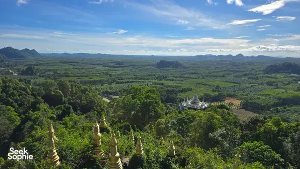 Aerial view over Khao Sok rainforest canopy with scattered white-and-gold pagodas and valleys in Khao Sok National Park