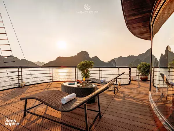 Balcony on the La Casta Cruise with wicker sun loungers and towels, overlooking choppy waters at dusk in Halong Bay