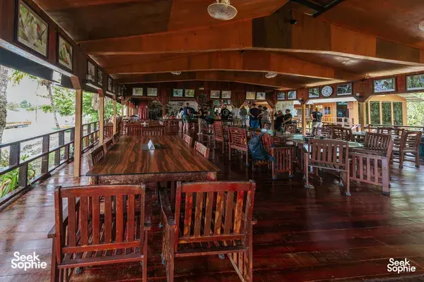 Spacious wooden dining room with chairs and large windows for a 2D1N safari stay in Sandakan along the Kinabatangan River