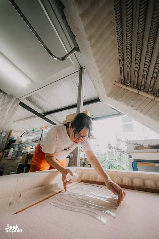 Art Glass Centre Singapore studio: a glass artist gently shaping a centrepiece with hands and tools amid surfaces — workshops in Singapore