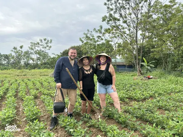 Travellers planting young rice in a muddy paddy at Duong Lam ancient village near Hanoi, led through a hands-on routine
