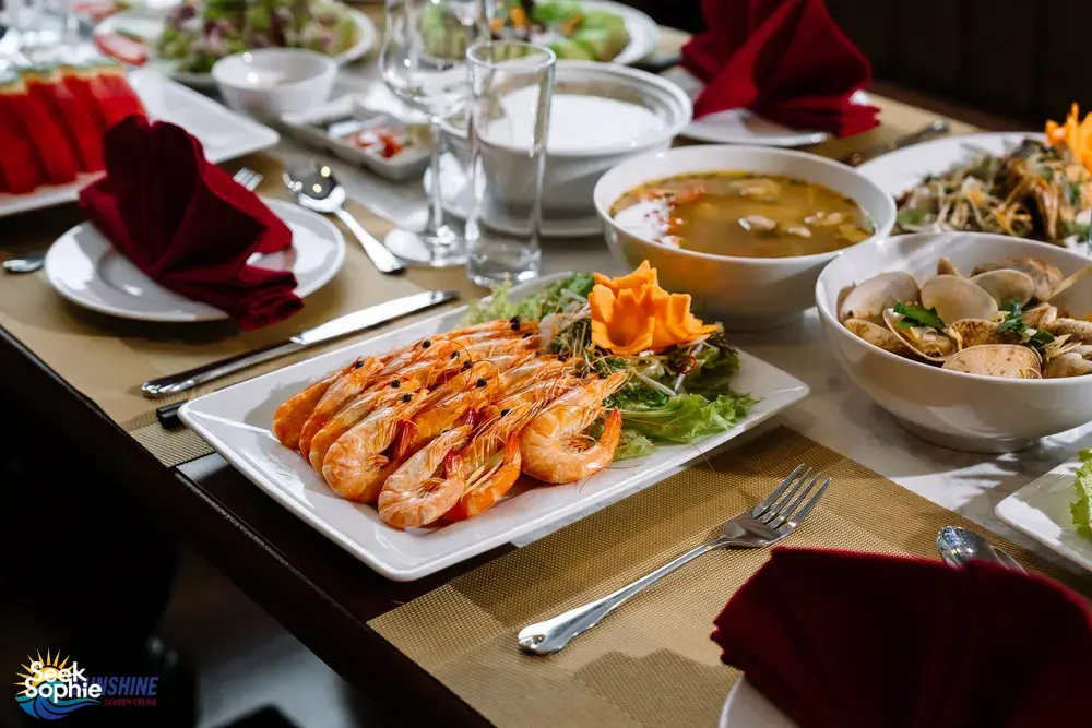 Platter of prawns and bowls of soup on a dining table, set for dinner on a Sunshine Golden Cruises luxe 2D1N Cat Ba cruise