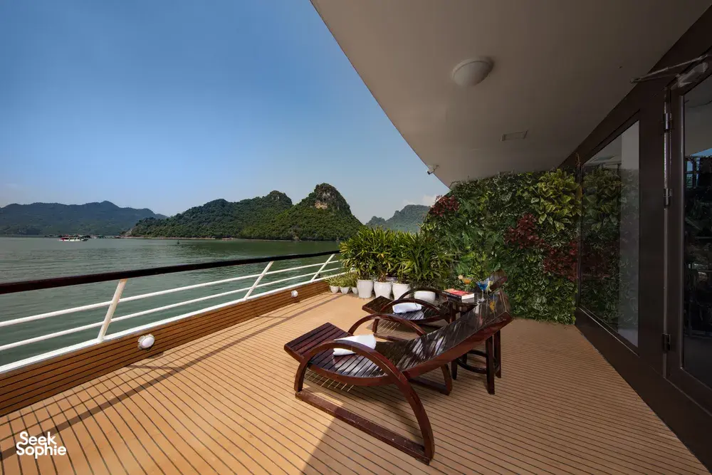 Sun deck on the Oasis Bay Party Cruiser with two wooden loungers, potted plants and lagoon views of surrounding islands on the Halong Bay