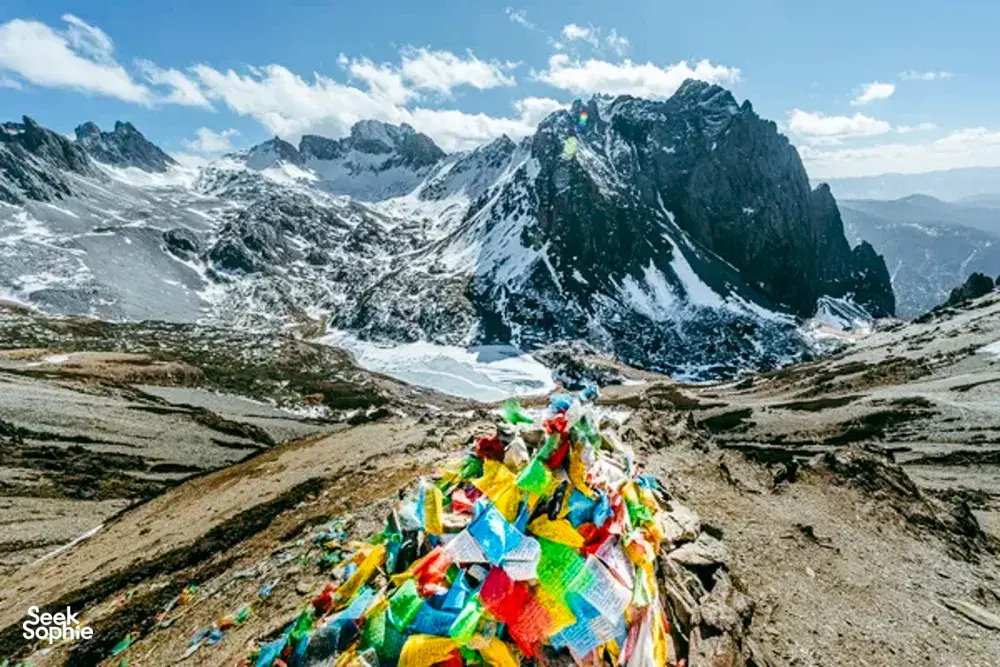 Colourful prayer flags overlooking snow-capped peaks and a valley in Shangri-La, along the Tiger Leaping Gorge trek