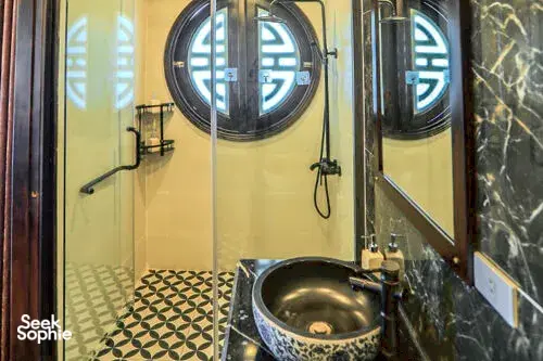 Cat Ba Ocean Cruises bathroom with round mirrors, a stone basin and patterned floor tiles, for onboard comfort on Cat Ba