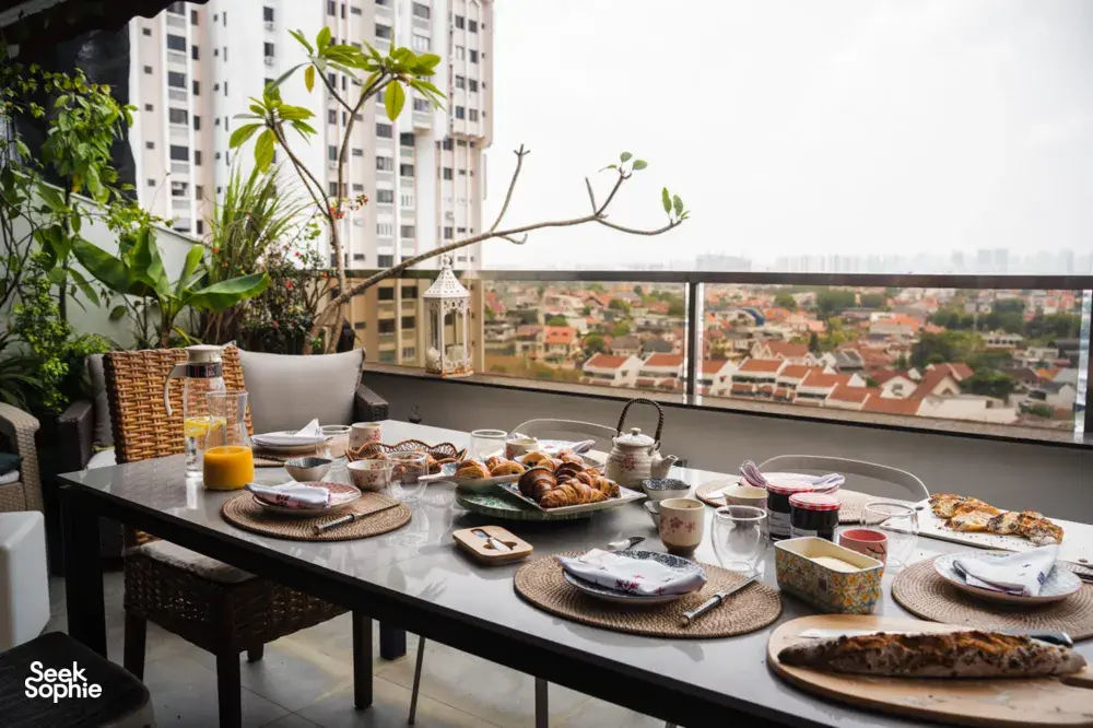 Breakfast table set on a Singapore balcony with croissants, cups and plates overlooking the city skyline — workshops in Singapore