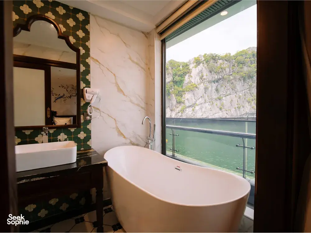 Private on-board bath on a 2D1N Cat Ba cruise with Sunshine Golden Cruises, overlooking calm green water and limestone cliffs