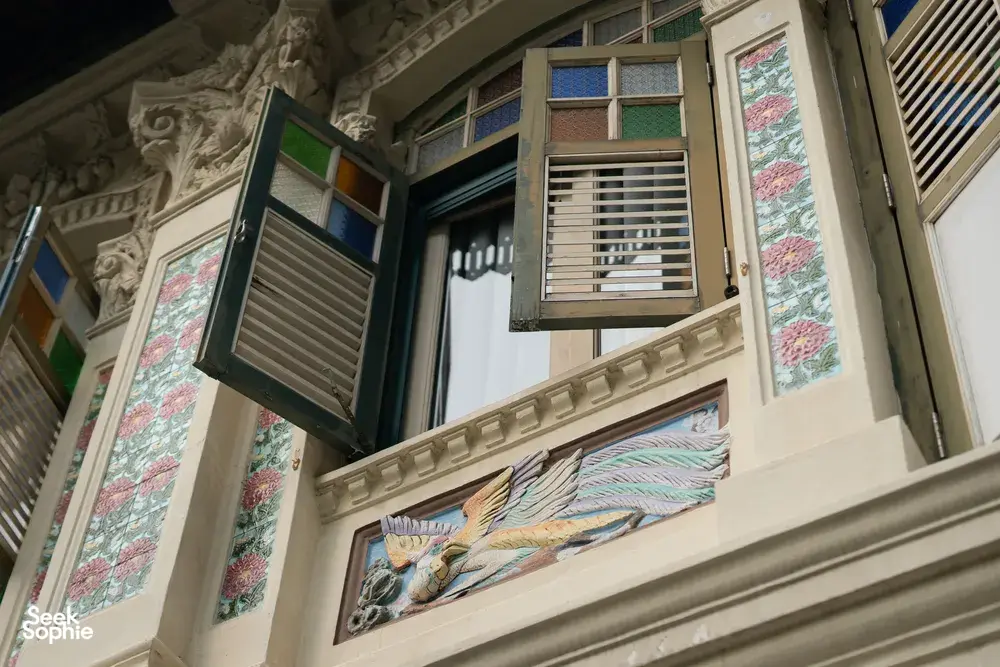 Heritage building exterior with decorative shutters and a painted window panel under arched stonework, Singapore hidden gems