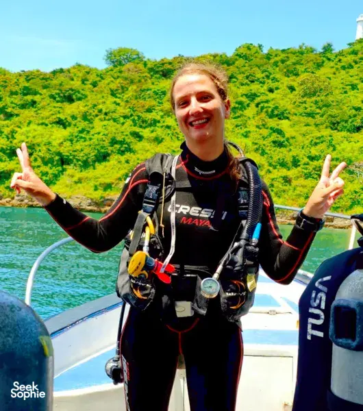 Scuba Froggy diver smiling with peace signs in scuba gear on a boat in Lombok, ready for macro dives at Pink Beach