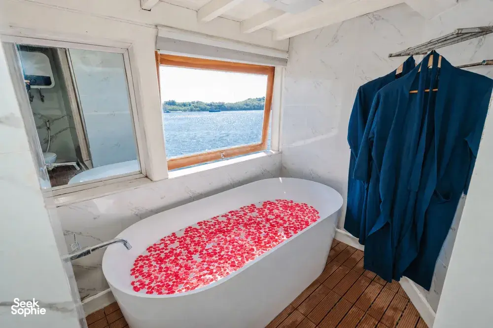 La Famille private 3D2N Komodo boat trip cabin with sea-view window and white bath fitted with red details, Labuan Bajo