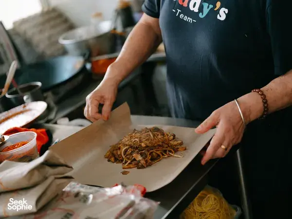 Hands spreading a mound of shredded noodles onto parchment during the Joo Chiat food tour, Singapore hidden gems