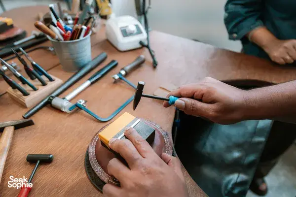 Hands shaping a silver ring with metal tools on a wooden bench at Fat Anvil Studios in Singapore â workshops in Singapore