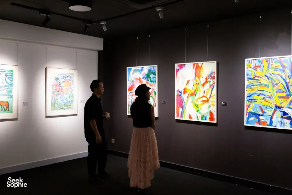 Visitors standing before framed paintings on gallery walls at Quang San Art Museum during a Vietnamese art tour in Ho Chi Minh City