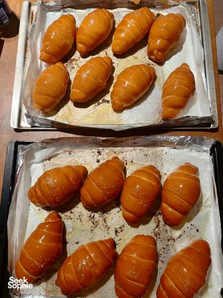 Golden shio pan rolls lined on baking trays at a The Daily Staples bread-making class in Singapore, ready to cool after baking