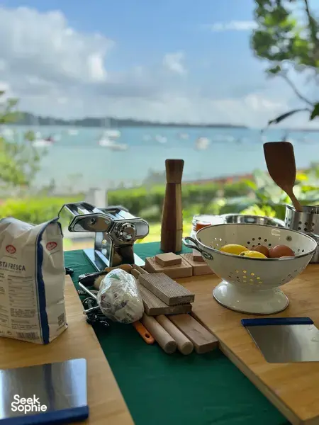Breakfast cooking setup on a wooden table with a colander of eggs, looking out to the sea at The Unexpected’s Singapore farmstay