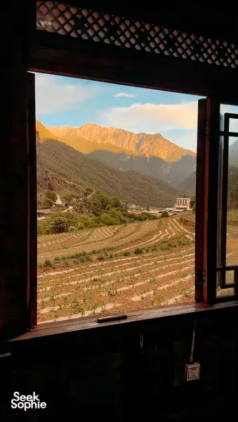 View of mountain range and terraced fields in Shangri-La seen from a room during a 6-day Tibetan guide trek