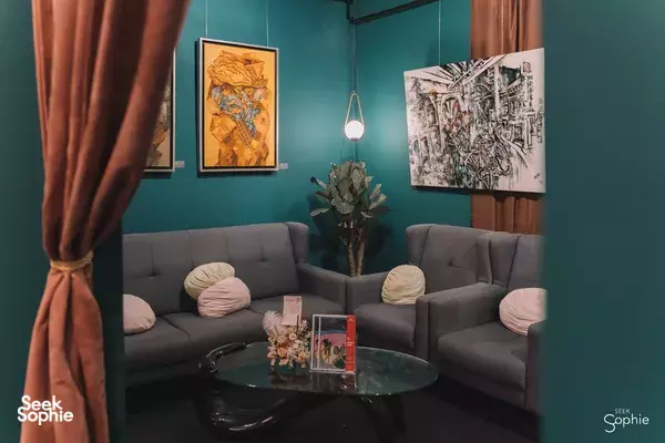Quiet lounge area in Avant-Garde Art Space studio in Singapore with grey sofas, a glass coffee table and colourful wall artwork