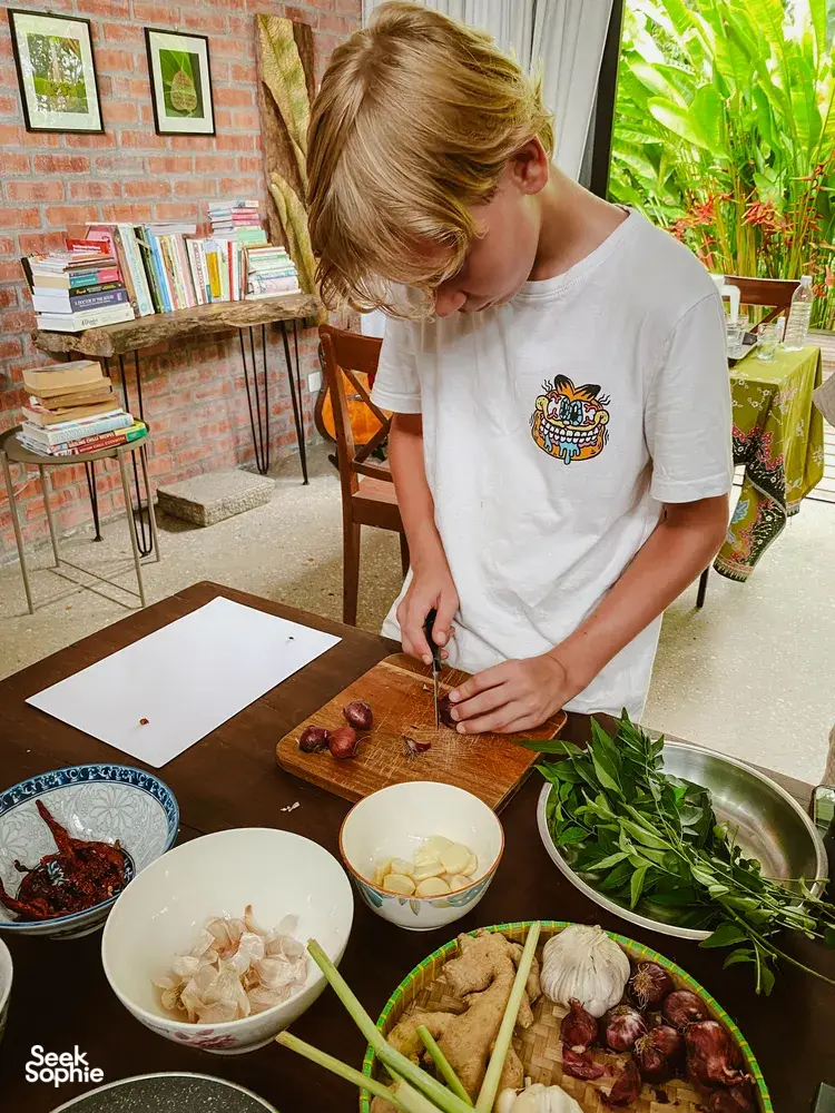 Chopping fresh herbs for Malaysian comfort food at a Kebun Lidstari kitchen prep table in Langkawi farmhouse