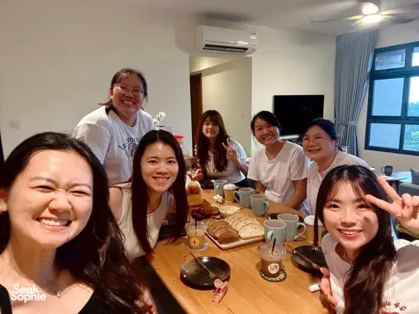 Smiling participants gathered around a wooden table with cups and bread during a focaccia class, workshops in Singapore