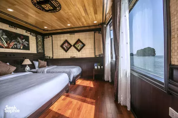 Twin beds in a Cat Ba Ocean Cruises cabin with an ocean view through the large window during a 2D1N Cat Ba cruise