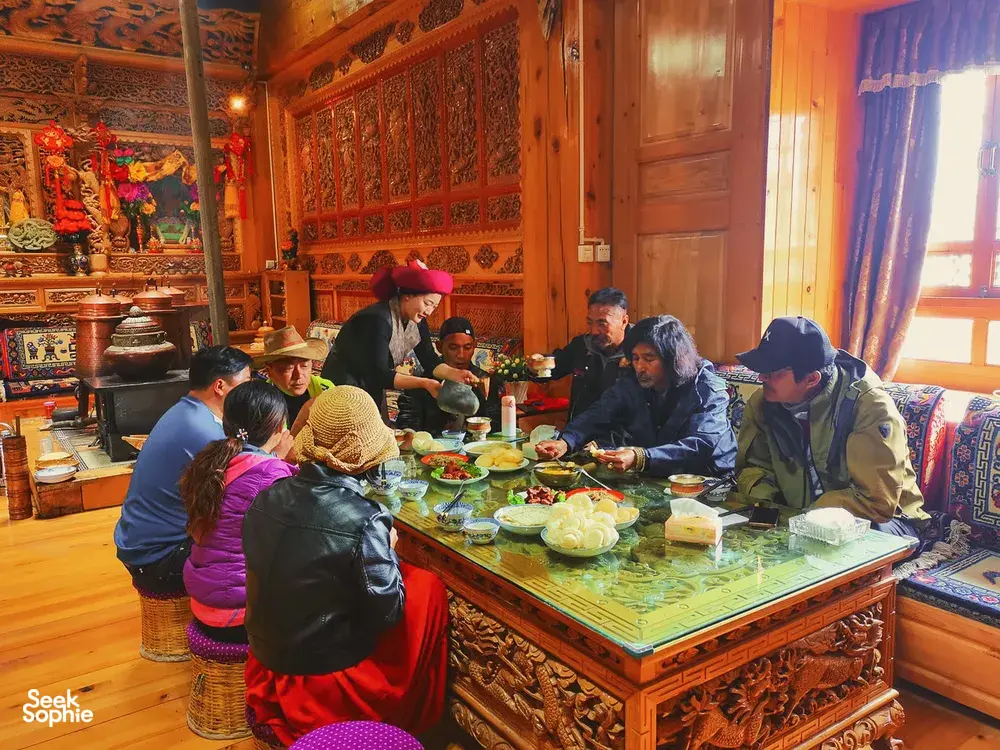 Guests sharing a Tibetan home lunch around a decorated table in Shangri-La, host-led by Khampa Caravan in a traditional room