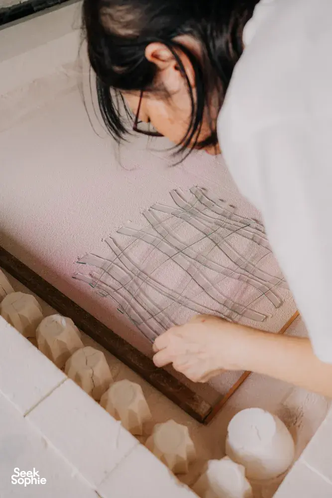 Participant’s hands placing glass tiles on a grid template at Art Glass Centre in Singapore — workshops in Singapore