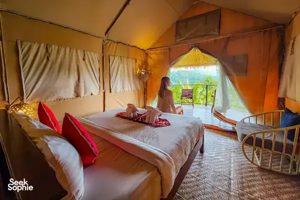 Khaosok Discovery luxe glamping tent with a queen bed and a guest relaxing, facing green valley views in Khao Sok National Park