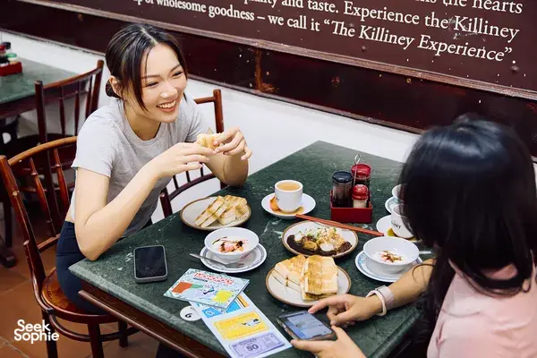 Friends playing a real-life Monopoly game at a Singapore River café, reviewing cards over brunch—Singapore hidden gems
