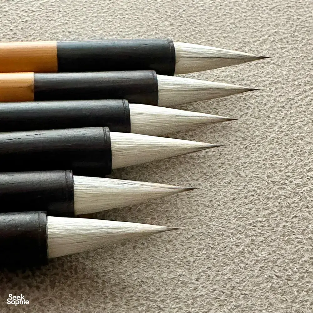 Pointed Chinese calligraphy brushes lined up on a textured surface for practising brushstrokes—workshops in Singapore
