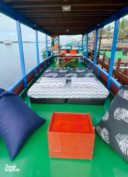 Boat cabin on a Sister Tour Tanjung Puting small-boat cruise, with cushioned berths and a chest on the green floor