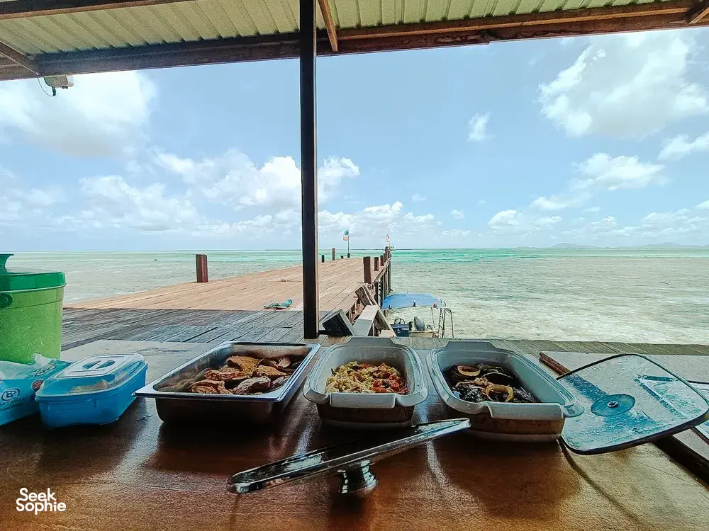 Diving gear laid out on the deck at Luma Selakan sea lodge, Semporna, with turquoise water and open horizon beyond