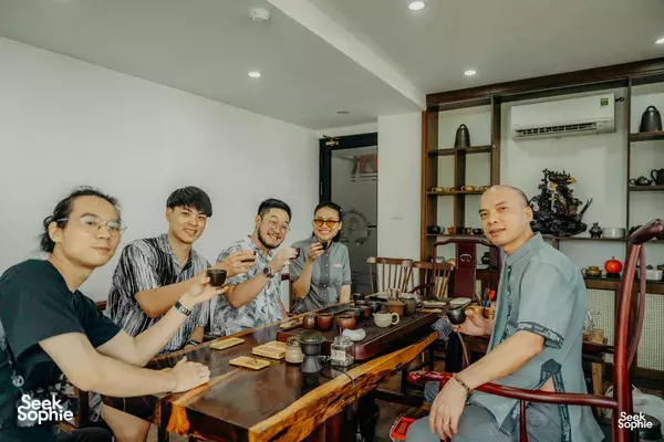 Group gathered around a wooden counter with small tea cups during a rare agarwood tour in Hanoi, learning together