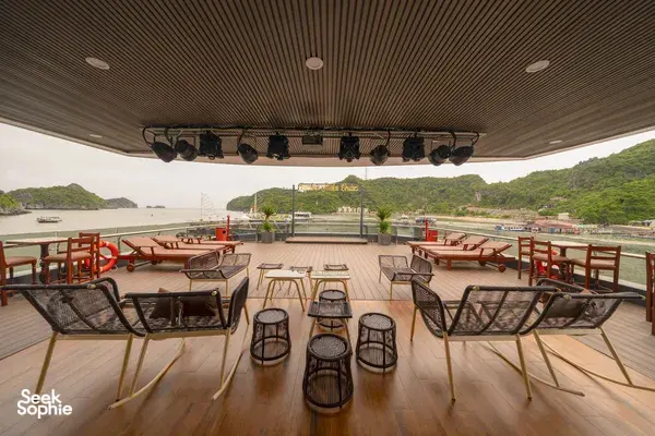 Sunshine Golden Cruises sundeck lounge with cushioned chairs and shelter, overlooking the bay and green hills in Cat Ba
