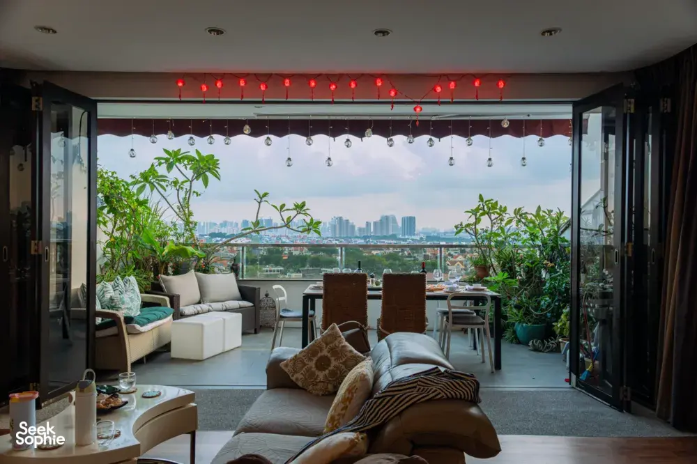 View into a cosy Singapore loft with string lights and city skyline through open doors, plants by the dining table