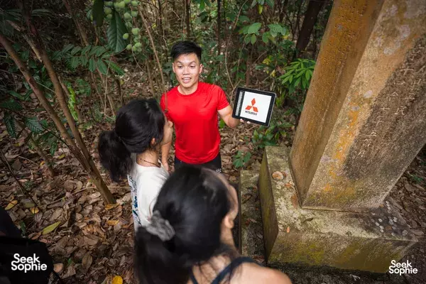 Tour guide in red explains wartime war-ruin details to hikers near concrete remnants at Mount Faber, Singapore — Singapore hidden gems