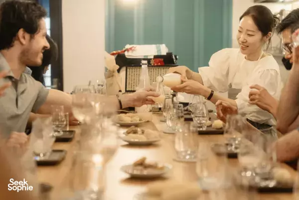 Cocktail making class in Ho Chi Minh City: friends pour and mix drinks together at a long table of bottles and glasses