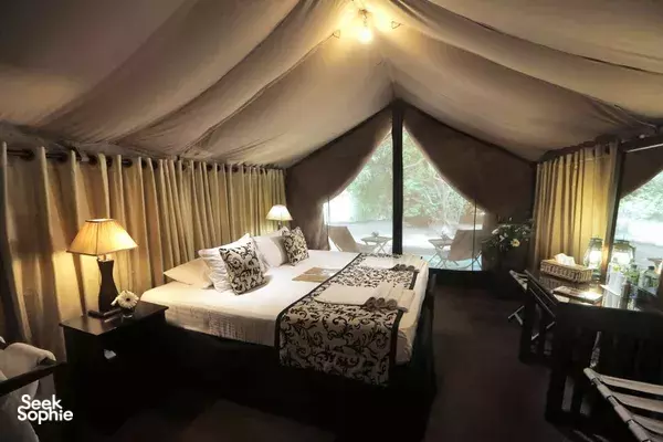 Leopard Trails luxury tent bedroom in Wilpattu, with neatly made bed, patterned pillows, and warm bedside lamps